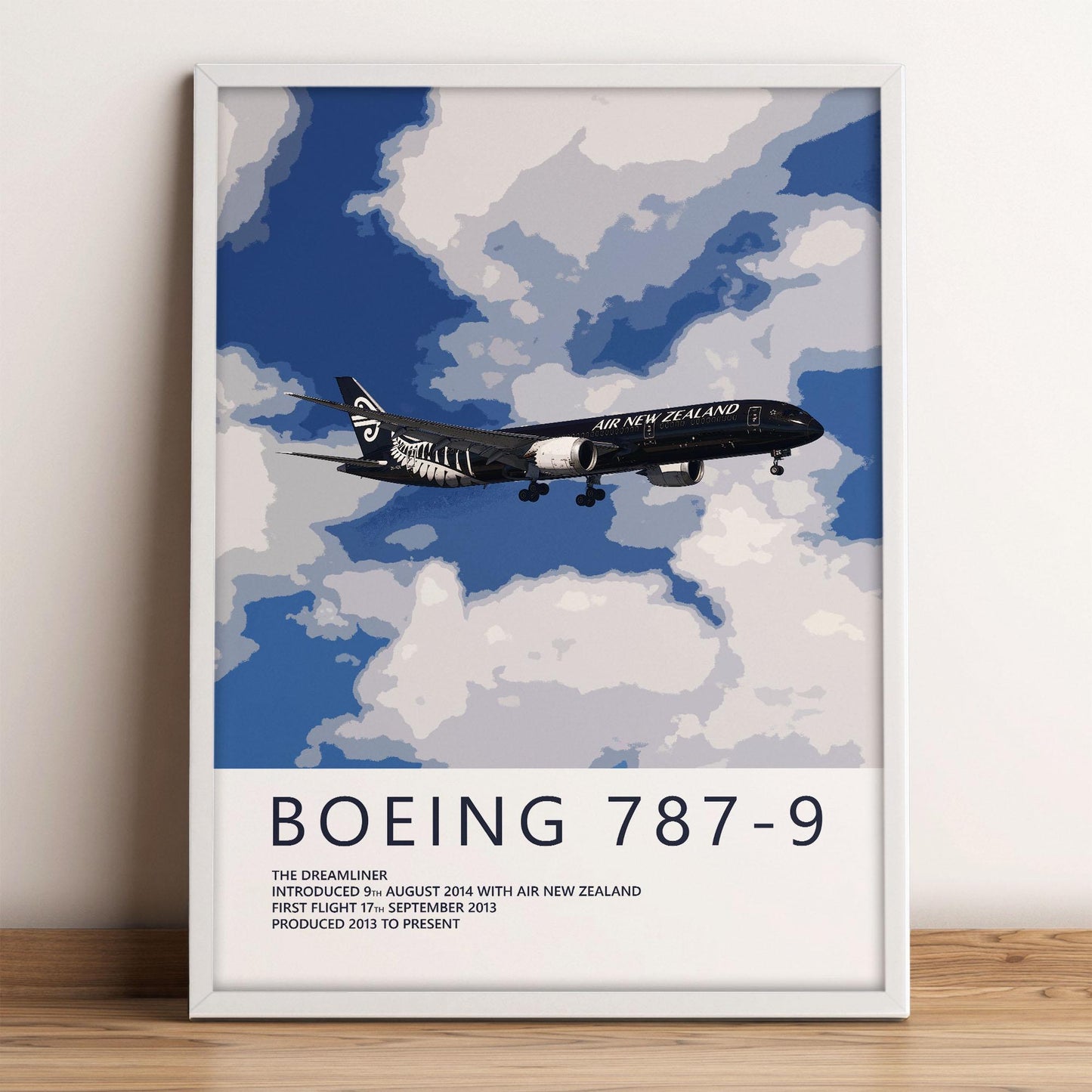 The image is a framed poster depicting a Boeing 787-9 airplane flying through a cloudy sky.