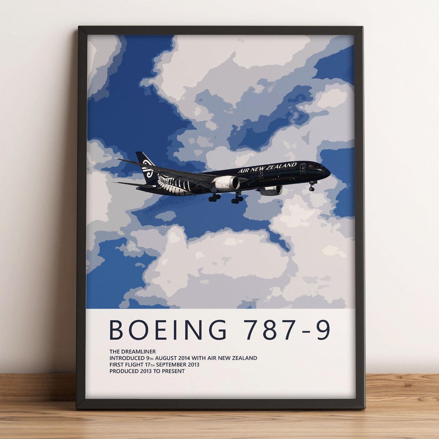 The image is a framed poster depicting a Boeing 787-9 airplane flying through a cloudy sky.
